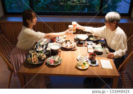 旅館の夕食で親子が乾杯を交わす温かい団らんのひととき 旅館の夕食で親子が乾杯を交わす温かい団らんのひととき 133948425
