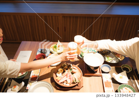 旅館の夕食で親子が乾杯を交わす温かい団らんのひととき 旅館の夕食で親子が乾杯を交わす温かい団らんのひととき 133948427