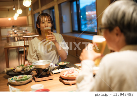 旅館の夕食で親子がビールを楽しむ穏やかなひととき 133948488