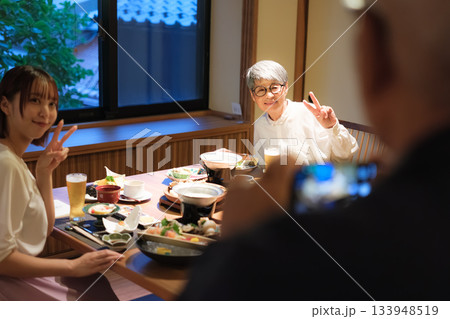 旅館の夕食で親子三人が撮り合いながら楽しむ思い出づくりの時間 133948519
