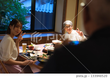 旅館の夕食で親子三人が撮り合いながら楽しむ思い出づくりの時間 133948520