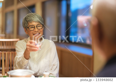 旅館の夕食でシニア夫婦がお酌を交わす温かいひととき 133948602