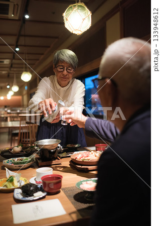 旅館の夕食でシニア夫婦がお酌を交わす温かいひととき 133948612