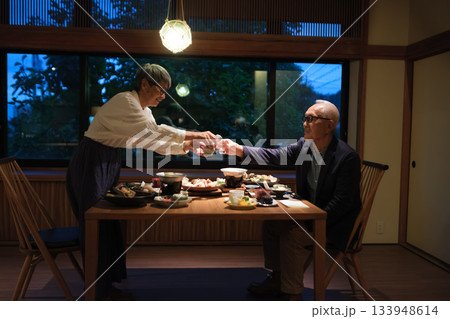 旅館の夕食でシニア夫婦がお酌を交わす温かいひととき 133948614