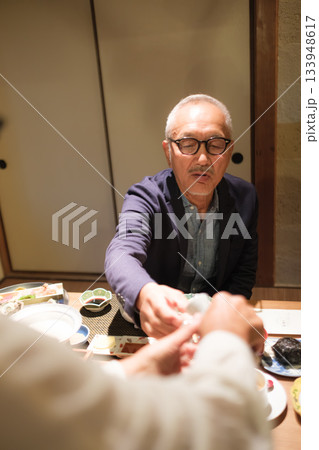 旅館の夕食でシニア夫婦がお酌を交わす温かいひととき 旅館の夕食でシニア夫婦がお酌を交わす温かいひととき 133948617