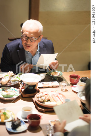 旅館の夕食でシニア夫婦がメニュー表を見ながら団らんを楽しむひととき 旅館の夕食でシニア夫婦がメニュー表を見ながら団らんを楽しむひととき 133948657