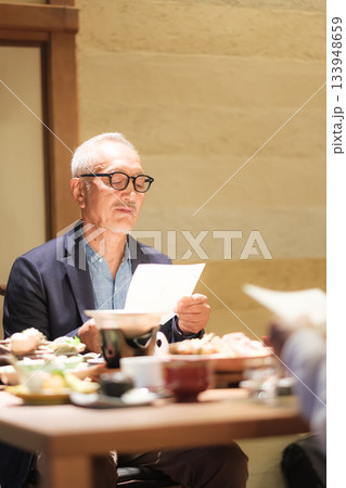 旅館の夕食でシニア夫婦がメニュー表を見ながら団らんを楽しむひととき 133948659
