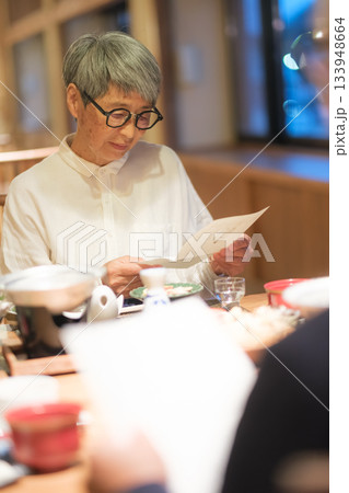 旅館の夕食でシニア夫婦がメニュー表を見ながら団らんを楽しむひととき 133948664