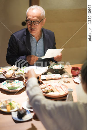 旅館の夕食でシニア夫婦がメニュー表を見ながら団らんを楽しむひととき 旅館の夕食でシニア夫婦がメニュー表を見ながら団らんを楽しむひととき 133948665