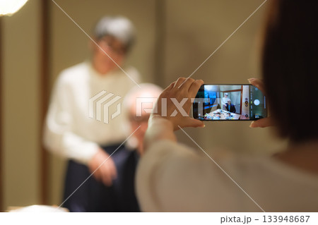 家族旅行の夕食で娘に還暦祝いの記念写真を撮ってもらうシニア夫婦 家族旅行の夕食で娘に還暦祝いの記念写真を撮ってもらうシニア夫婦 133948687