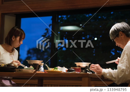 母娘で迎える還暦祝いの旅。旅館の静かな夕食で、温かな時間を分かち合う二人 133948795