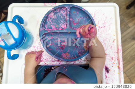 Baby Enjoying a Messy Meal in High Chair 133948820
