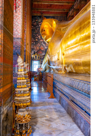 Golden reclining Buddha statue inside Wat Pho temple in Bangkok, Thailand, captured in a grand perspective showing its monumental scale and serene spiritual atmosphere. 133948881