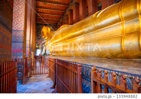 Golden reclining Buddha statue inside Wat Pho temple in Bangkok, Thailand, captured in a grand perspective showing its monumental scale and serene spiritual atmosphere. 133948882