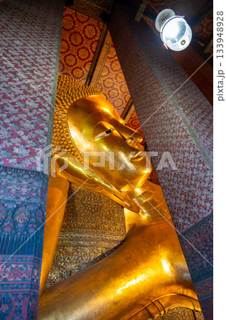 Golden reclining Buddha statue inside Wat Pho temple in Bangkok, Thailand, captured in a grand perspective showing its monumental scale and serene spiritual atmosphere. Golden reclining Buddha statue inside Wat Pho temple in Bangkok, Thailand, captured in a grand perspective showing its monumental scale and serene spiritual atmosphere. 133948928