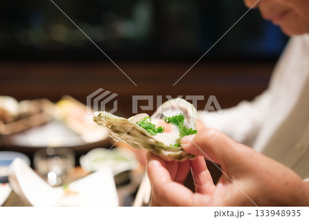シニア夫婦が還暦祝いの旅行で旅館の会席料理をゆったり味わう夕食シーン 133948935