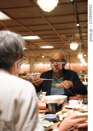 シニア夫婦が還暦祝いの旅行で旅館の会席料理をゆったり味わう夕食シーン シニア夫婦が還暦祝いの旅行で旅館の会席料理をゆったり味わう夕食シーン 133948952