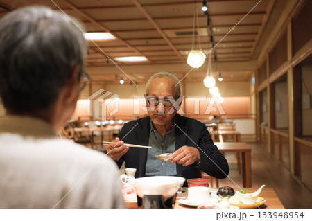シニア夫婦が還暦祝いの旅行で旅館の会席料理をゆったり味わう夕食シーン シニア夫婦が還暦祝いの旅行で旅館の会席料理をゆったり味わう夕食シーン 133948954
