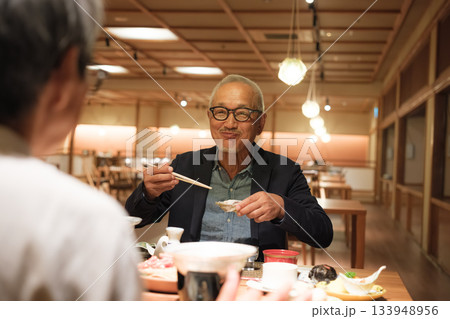 シニア夫婦が還暦祝いの旅行で旅館の会席料理をゆったり味わう夕食シーン シニア夫婦が還暦祝いの旅行で旅館の会席料理をゆったり味わう夕食シーン 133948956