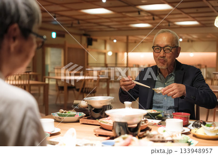 シニア夫婦が還暦祝いの旅行で旅館の会席料理をゆったり味わう夕食シーン シニア夫婦が還暦祝いの旅行で旅館の会席料理をゆったり味わう夕食シーン 133948957
