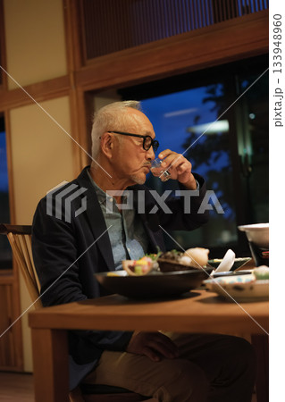 シニア夫婦が還暦祝いの旅行で旅館の会席料理をゆったり味わう夕食シーン シニア夫婦が還暦祝いの旅行で旅館の会席料理をゆったり味わう夕食シーン 133948960