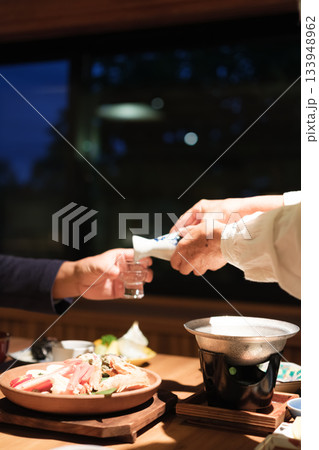 シニア夫婦が還暦祝いの旅行で旅館の会席料理をゆったり味わう夕食シーン シニア夫婦が還暦祝いの旅行で旅館の会席料理をゆったり味わう夕食シーン 133948962