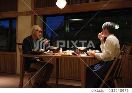 シニア夫婦が還暦祝いの旅行で旅館の会席料理をゆったり味わう夕食シーン シニア夫婦が還暦祝いの旅行で旅館の会席料理をゆったり味わう夕食シーン 133948971
