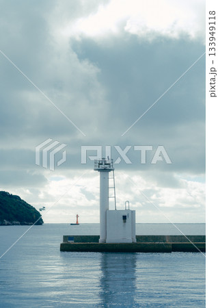 山あいの町に広がる静かな漁港風景。穏やかな水面に並ぶ漁船とローカルな町並み 133949118