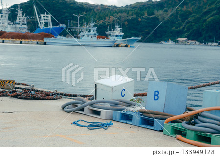 山あいの町に広がる静かな漁港風景。穏やかな水面に並ぶ漁船とローカルな町並み 133949128
