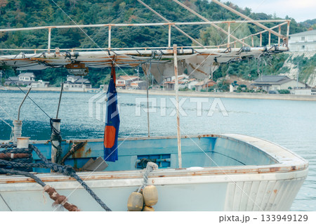 山あいの町に広がる静かな漁港風景。穏やかな水面に並ぶ漁船とローカルな町並み 133949129