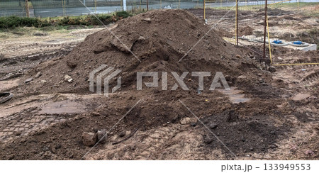 Construction site with a large mound of dirt and heavy machinery tracks Construction site with a large mound of dirt and heavy machinery tracks 133949553