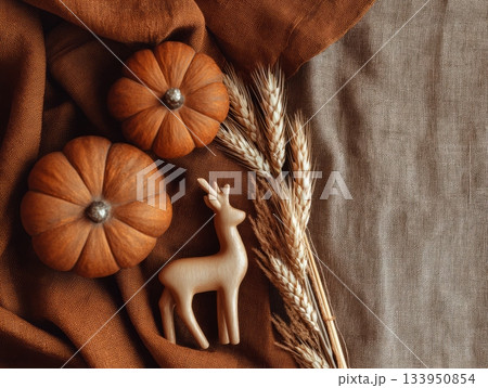 Autumn flatlay with pumpkins, dried wheat and wooden deer on linen fabric 133950854