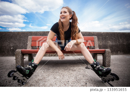 Happy young woman wearing roller skates Happy young woman wearing roller skates 133951655