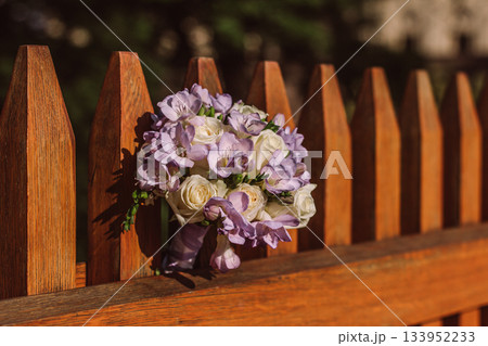 Wedding bouquet resting on wooden fence in sunlight 133952233