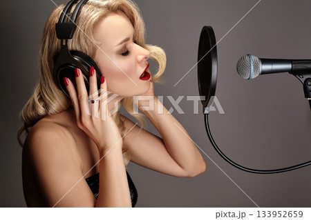 Blonde Woman Singing Song in Recording Studio with Microphone, Headphones. Glamour Diva Creates Musical Track. Karaoke Blonde Woman Singing Song in Recording Studio with Microphone, Headphones. Glamour Diva Creates Musical Track. Karaoke 133952659