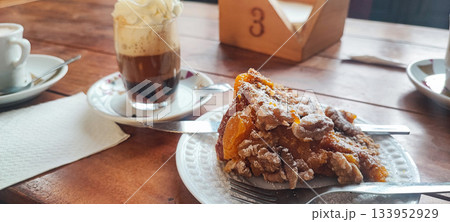 A close-up of a glass of hot coffee with cream and a fruit nut pie. Concept: coffee break, hospitality, and homemade baked goods. A close-up of a glass of hot coffee with cream and a fruit nut pie. Concept: coffee break, hospitality, and homemade baked goods. 133952929