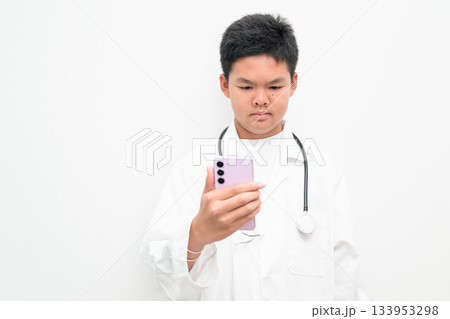 Young Asian Boy Dressed as Doctor with Stethoscope Using Mobile Phone Young Asian Boy Dressed as Doctor with Stethoscope Using Mobile Phone 133953298