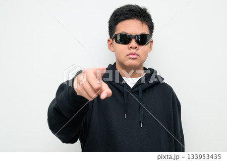 Asian Teenage Boy in Hoodie Wearing Sunglasses Pointing at Camera Asian Teenage Boy in Hoodie Wearing Sunglasses Pointing at Camera 133953435