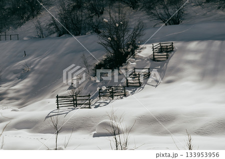 Snow-covered landscape with wooden fences in a remote area during winter 133953956