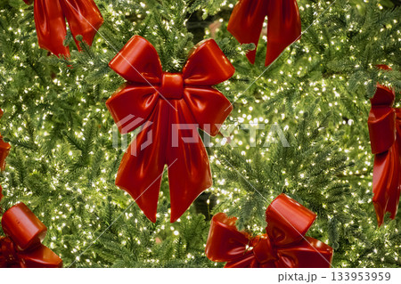 Shiny red bows decorating a Christmas tree full of sparkling warm lights. Festive and joyful holiday atmosphere. 133953959