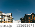 Snowy buildings under clear blue sky in mountain location during winter season 133953975
