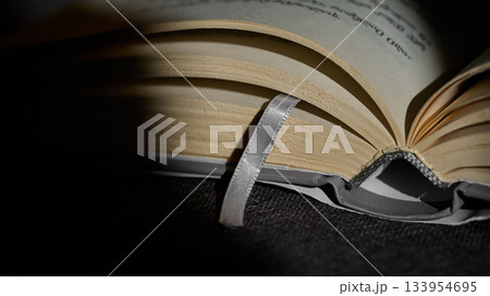 Open book with a ribbon bookmark on dark surface. High quality photo 133954695