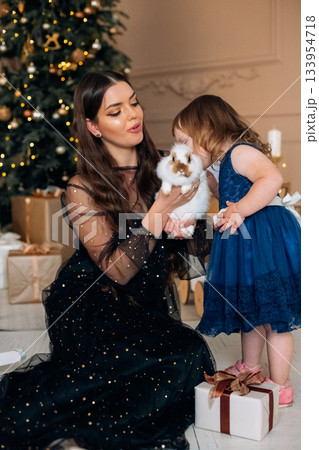 Celebrating the holiday season with a child and a bunny in a beautifully decorated living room filled with festive gifts and a Christmas tree 133954718