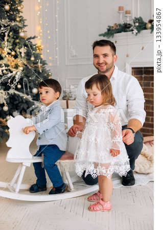 Family joy during a festive holiday gathering with children in a cozy decorated living room Family joy during a festive holiday gathering with children in a cozy decorated living room 133954867