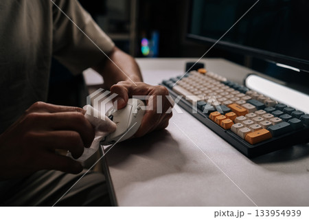 Close-up of man disinfecting computer mouse with white wet wipe, ensuring cleanliness and hygiene on desktop accessories near keyboard, promoting health and maintenance for office equipment. Close-up of man disinfecting computer mouse with white wet wipe, ensuring cleanliness and hygiene on desktop accessories near keyboard, promoting health and maintenance for office equipment. 133954939