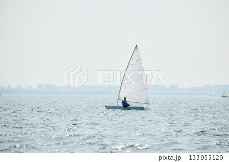 Russia, St. Petersburg, The sports sailing dinghy is heeling at sunny day, athletes tilt the boat, speed and spray, reflection of sun on water surface 133955120