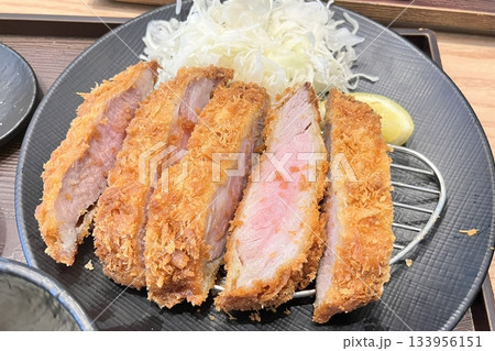 Crispy tonkatsu, a Japanese-style breaded and deep-fried pork cutlet, served with shredded cabbage and drizzled with savory sauce. A delightful balance of crunchy texture and juicy meat. 133956151