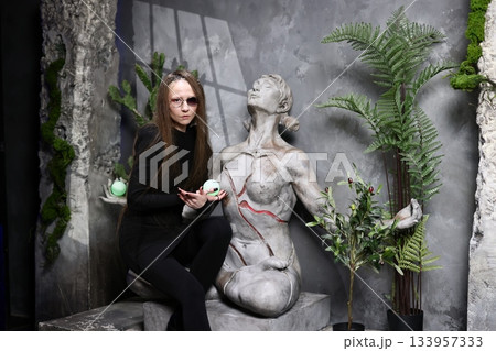 Woman gestures with bright green sphere near ancient stone statue Woman gestures with bright green sphere near ancient stone statue 133957333
