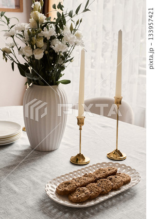 Comfortable table setting with flowers, Inviting cozy dining scene with candles and cookies 133957421