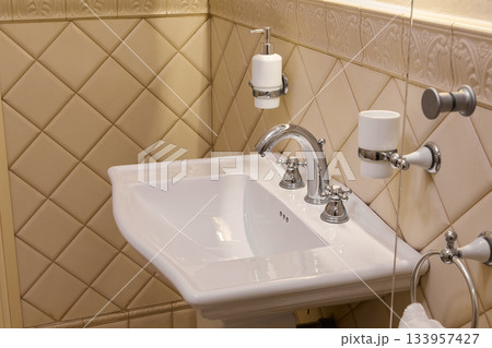 Stylish porcelain sink with fittings, Charming antique bathroom with glossy basin and fixtures 133957427